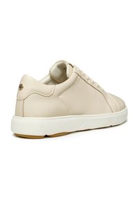 Sneaker de cuero beige con una suela blanca, punta redondeada, cordones tonales y un sutil logo en el talón. Textura suave con costuras mínimas.