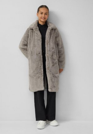 Faux-Fur-Mantel in Hellgrau mit Knopfverschluss, übergroßem Kragen und strukturiertem Stoff, kombiniert mit schwarzen Hosen und weißen Sneakers.