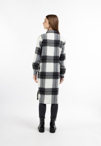 Sort og hvidt ternet langt skortkjole lavet af blødt stof, med krave, lange ærmer og sideslids. Stylet over mørke leggings og støvler.