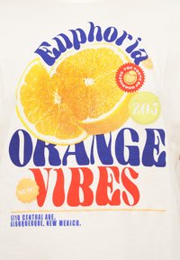 Λευκό μπλουζάκι με μεγάλο γραφικό από μισά πορτοκάλια, έντονο κείμενο που γράφει "Euphoria Orange Vibes" και διάφορα πολύχρωμα κυκλικά διακοσμητικά.