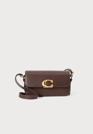 Sac bandoulière en cuir marron avec un logo en accent doré, de forme rectangulaire, fermeture à rabat et une sangle réglable.