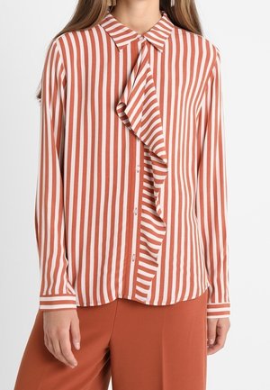 Blusa a righe in ruggine e bianco, con un inserto frontale arricciato, colletto e chiusura con bottoni. Maniche lunghe con polsini a righe.