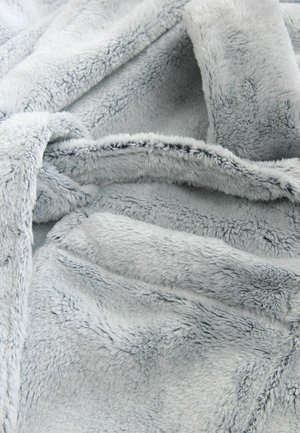 Vaaleanharmaa keinoturkista valmistettu lämmittelyhuopa, jossa on pehmeä, teksturoitu pinta, joka tuo esiin ylellisen tuntuman ja hellävaraisen kiillon, laskostettuna, paljastaen vaihtelevaa syvyyttä.