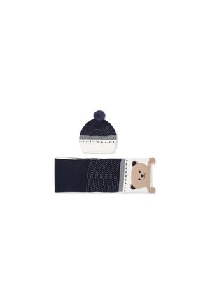 Cappello lavorato a maglia blu navy con pom pon in cima e fascia crema, abbinato a una sciarpa coordinata con design di faccia d'orso e accenti a motivo.