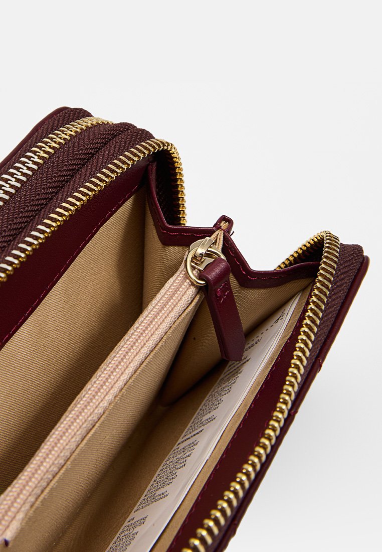 Bordo portfel o fakturowanej powierzchni, złotym zamku błyskawicznym i beżowym wnętrzu. Posiada kieszeń na zamek oraz wiele slotów na karty.