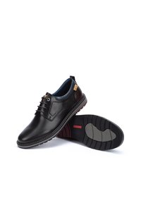 Zwarte leren schoenen met vetersluiting, ronde neus, contrasterende bruinaccenten en een rubberen zool met een gestructureerde grip.