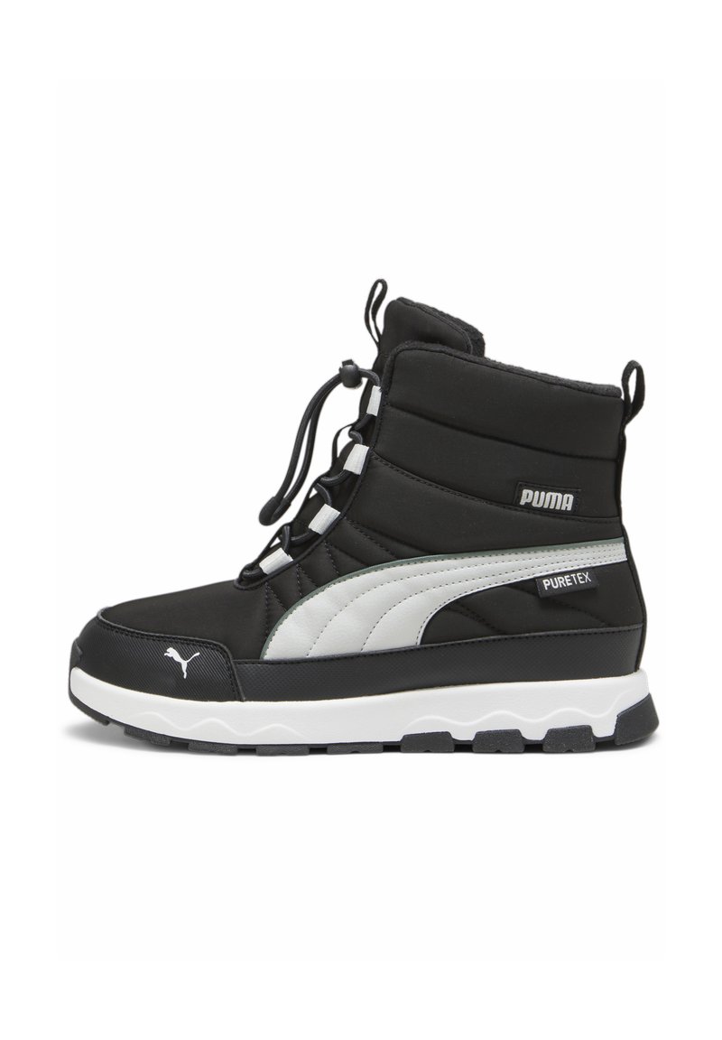 Zapatilla negra de caña baja con textura acolchada, detalles en blanco y gris, cierre de cordones y suela blanca con agarre texturizado.
