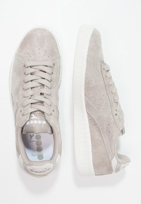 Graue Wildledersneakers mit einem Low-Top-Design, runden Zehen, Schnürsenkeln und weißen Gummisohlen mit subtilen Perforationen und Logodetails.