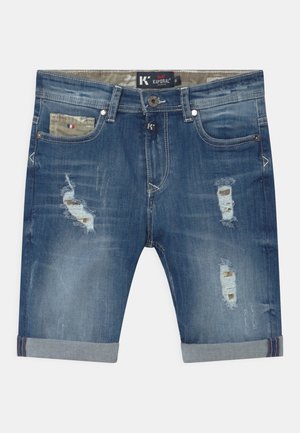 Denimshorts i mørkeblå med flosset materiale og slidte detaljer. Opkrullede kanter ved benene og en lomme med camouflageprint.
