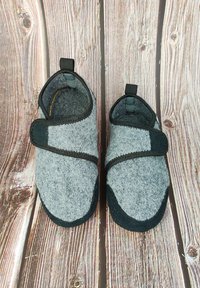 Grijze gevoerde slippers met zwarte accenten en verstelbare klittenbandsluitingen. Beschikt over een ronde neus en een gevoerde binnenkant voor comfort. Textuurzool.