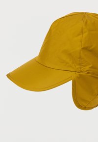 Kollane kork, millel on kõver läbipaistev lippa ja kõrvaklapid, valmistatud siledast, veekindlast materjalist. Omab lihtsat, ümarat disaini, millel on õmblustega kaunistused.