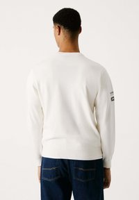Suéter blanco de manga larga con puños y dobladillo acanalados. Parche con el logo en la manga izquierda. Material suave y ligero con un corte clásico.