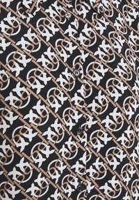 Zwarte stof met diagonale beige lijnen en herhalende witte en beige symmetrische kruispatronen, met een verticale rij zwarte knopen.