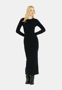 Schwarzes Langarmkleid mit geripptem Textur, versehen mit verstreuten kleinen Verzierungen, enganliegender Silhouette und knöchellangem Design.