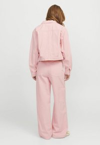 Ružičasta skraćena jakna i hlače širokog kroja s uzorkom vertikalnih pruga, s ležernim stilom, teksturiranim materijalom i bočnim džepovima.