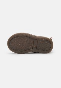 Semelle de chaussure brune en caoutchouc texturé, présentant une légère courbe au niveau de l'orteil, avec des motifs de semelle visibles et une empreinte de logo.