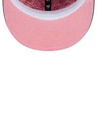 Pink snapback cap with a textured, floral-patterned interior lining, featuring a white band along the edge and contrasting black underside.