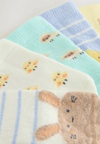 Vier Paar weiche Babysocken in Pastellfarben mit Mustern von Küken, Schafen, Streifen und einem Hasengesicht.