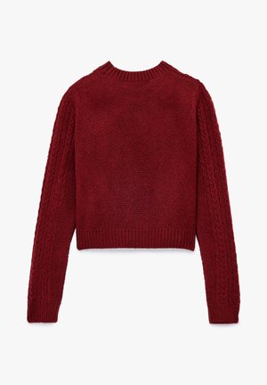 Pull cropped rouge avec un corps en tricot texturé. Accents en tricot torsadé sur les manches et col et ourlet côtelés.