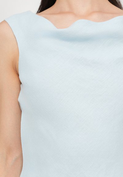 Ljust blå ärmlös topp i texturerad tyg med en vikbar halsringning och en figurnära silhuett som framhäver kroppens form.