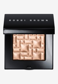 Bobbi Brown highlighter i en svart kompakt. Teksturert gullflate med et geometrisk mønster. Lukkemekanisme foran med en elegant finish.