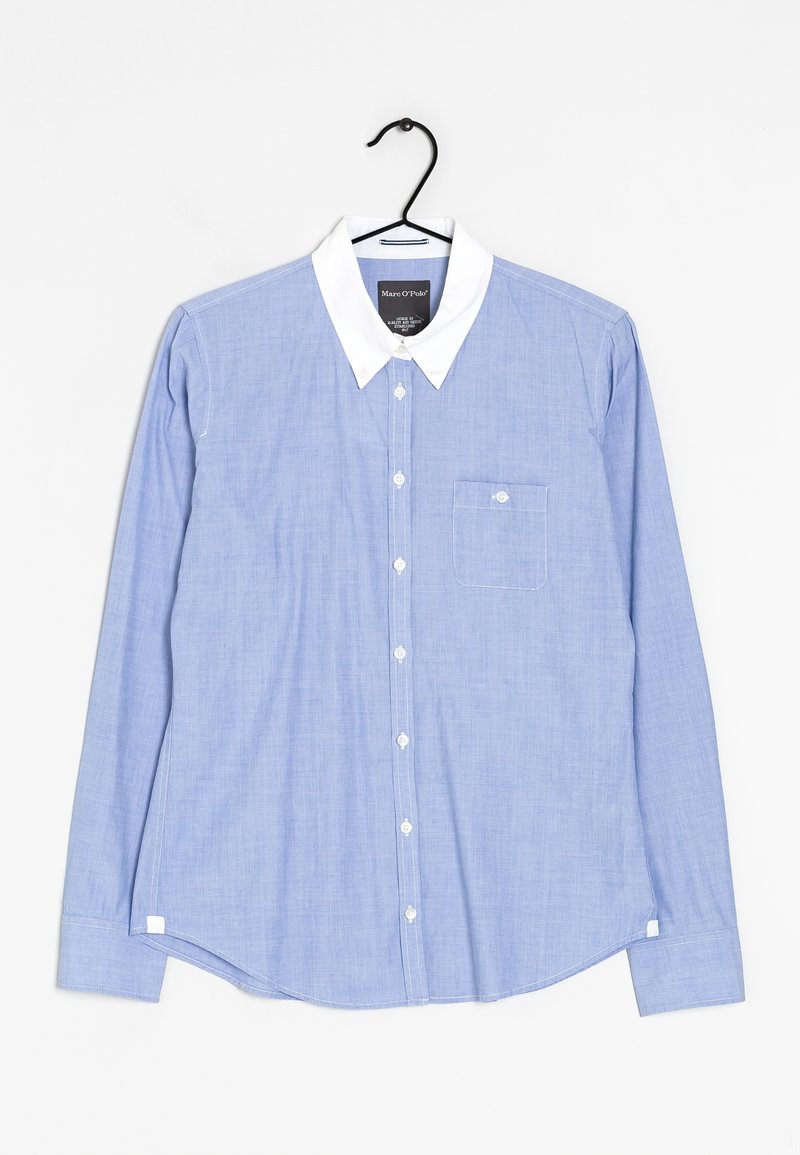 Chemise bleu clair à manches longues avec boutons, col blanc et poche poitrine, présentée sur un cintre noir sur fond blanc.