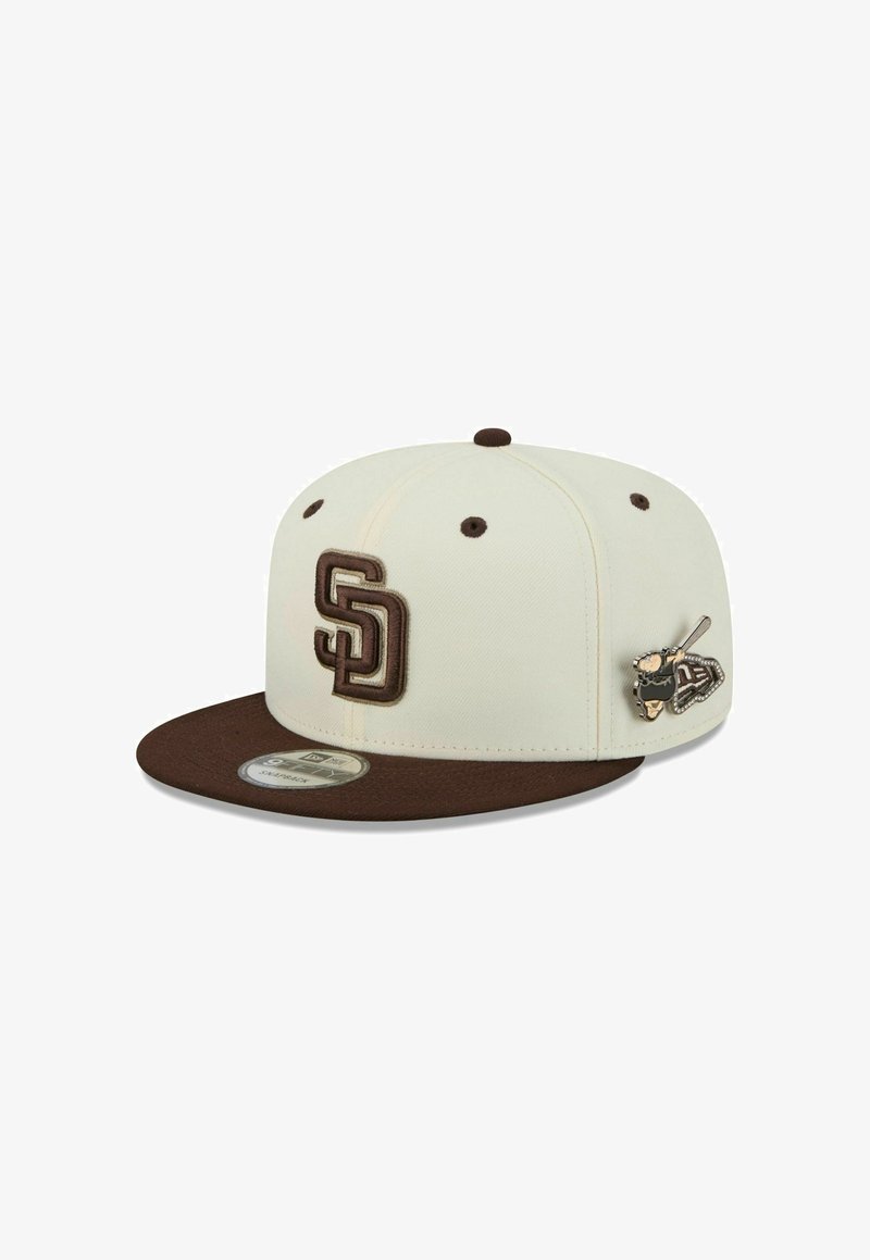 Casquette snapback crème et marron avec les initiales "SD" brodées sur le devant et une épingle de joueur de baseball sur le panneau latéral.