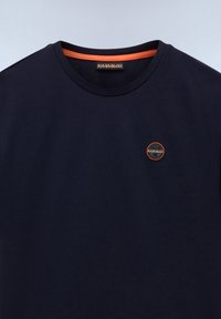 Granatowy t-shirt z okrągłym dekoltem, pomarańczową lamówką wewnątrz kołnierza i małą okrągłą naszywką z logo na lewej piersi.