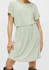 Světle zelené šaty s krátkým rukávem a volným střihem. Pas stažený gumičkou, měkká látka, délka po kolena, minimalistický design, bez viditelných vzorů.