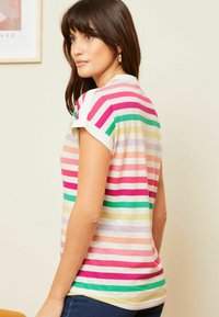 Trumpas rankovėmis, dryžuotas marškinėliai, kuriuose dominuoja rožinės, žalios, oranžinės ir geltonos spalvos. Lygus paviršius su baltu apykaklės ir rankogalių akcentu.