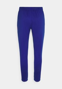 Blå atletiske slim-fit bukser med elastisk taljebånd, vist på en ensfarvet hvid baggrund.