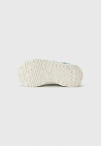 Semelle en caoutchouc pour sneaker, avec un motif de grip texturé, de couleur crème majoritaire, avec le logo "Converse" en relief sur le côté.