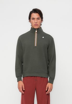 Sweatshirt à col montant et demi-zip de couleur vert foncé, orné de bandes multicolores sur le zipper et d'un logo sur la poitrine.