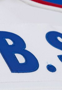 Tissu blanc présentant de grandes lettres bleues brodées avec un fini brillant. Le design comprend des coutures visibles et une texture lisse.