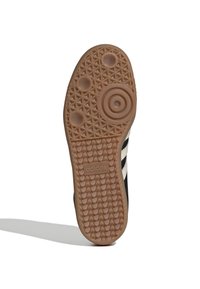 Černá podrážka tenisky s texturovaným designem z gumové pryže, obsahující kruhový vzor a tři kruhové prohlubně. Obsahuje značku "adidas".