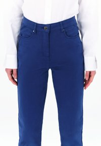 Blauwe katoenen broek van een stoffenmix met een getailleerd ontwerp, voorzien van een knoopsluiting en zijzakken, gestructureerd met een lichte glans en een gladde textuur.