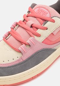 Višebojni Vans tenisice s ružičastim vezicama, odsuđene i kožne površine u ružičastoj, krem, sivoj i koraljnoj boji, ističući logo brenda na jeziku.