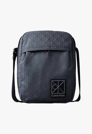 Ciemnoszara torebka na ramię Calvin Klein z subtelnym wzorem monogramu, przednią kieszenią na suwak i regulowanym czarnym paskiem.