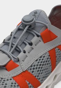 Γκρι και πορτοκαλί αθλητικό παπούτσι με διαπνέον δίχτυ, ελαστικά κορδόνια και πλαστικό κλείδωμα στο γλωσσίδι για ασφαλή ρύθμιση της εφαρμογής.