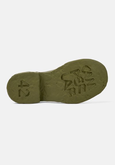 Green rubber sole featuring textured grip and geometric pattern. Size marked as 42, with a slightly rugged appearance and matte finish.