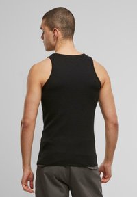 Schwarzes Tanktop aus strukturiertem Stoff, mit rundem Ausschnitt und weiten Armausschnitten. Das Design ist enganliegend und minimalistisch.