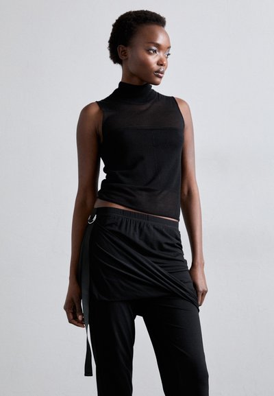 Top preto sem mangas com um pescoço alto, combinado com uma saia envolvente com um laço lateral. Ambas as peças têm uma textura suave e macia.