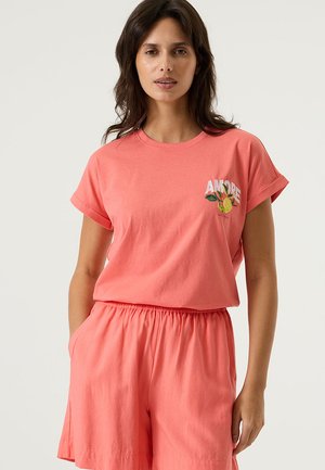 Koraalroze katoenen T-shirt met opgerolde mouwen, voorzien van "AMORE" borduursel en citrusontwerp. Gecombineerd met bijpassende koraalroze shorts met zakken.