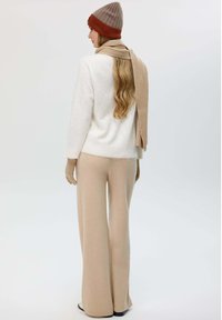 Maglione lavorato a maglia crema, pantaloni beige a gamba larga, cappello marrone a coste e sciarpa. Il maglione presenta una vestibilità comoda; la sciarpa e il cappello hanno bande a contrasto.