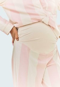 Lekki, miękki zestaw odzieży domowej z różowymi i kremowymi paskami. Posiada elastyczne marszczenie po bokach spodni oraz ozdobne guziki na koszuli.