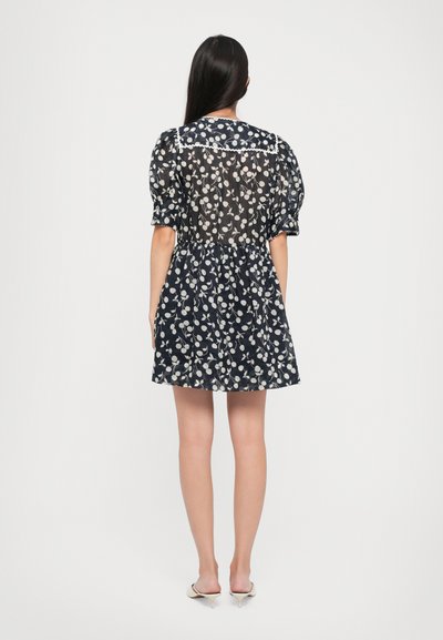 Rochie florală de marină cu spate transparent, mâneci bufante și talie strânsă. Prezintă o margine delicată albă pe guler.