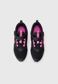 Baskets pour enfants Nike noires et roses avec des attaches Velcro et des lacets, vues de dessus sur un fond blanc.