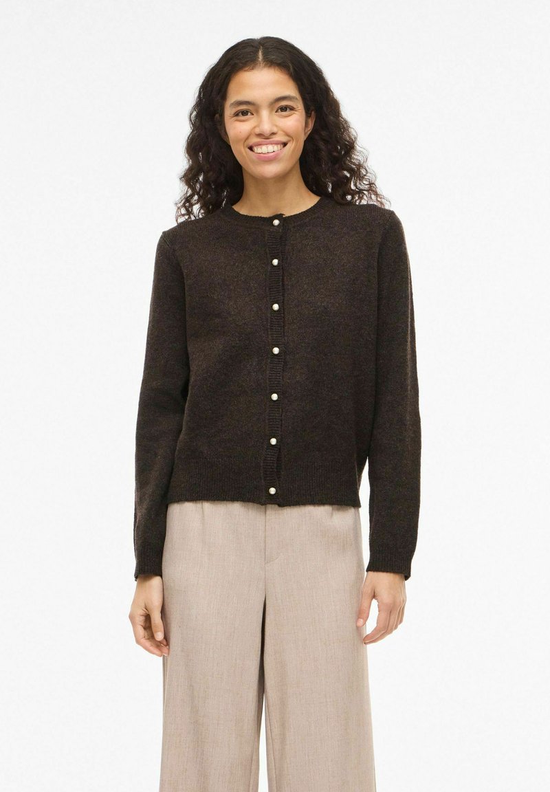 Mørk brun cardigan laget av teksturert stoff, med rund hals, knappestolpe foran med perleaktige knapper, og lange ermer.