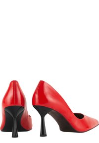 Des chaussures à talons hauts en cuir rouge avec un bout pointu et des côtés découpés, présentant un talon aiguille noir et une finition lisse et brillante.