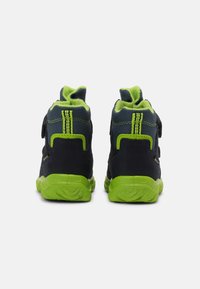 Sneakers alte nere e verdi con cinturini in Velcro, suole testurizzate e cuciture in contrasto. Fodera morbida verde nella parte superiore.